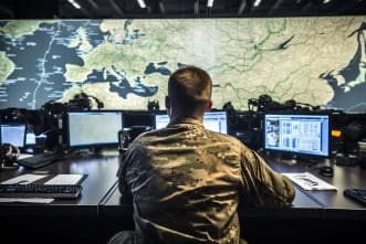 MilitaryMan Viewing Multiple Computer Screens in front of a map for New JADC2 Legislation Aims to Rapidly Prototype Cutting-Edge Technology.